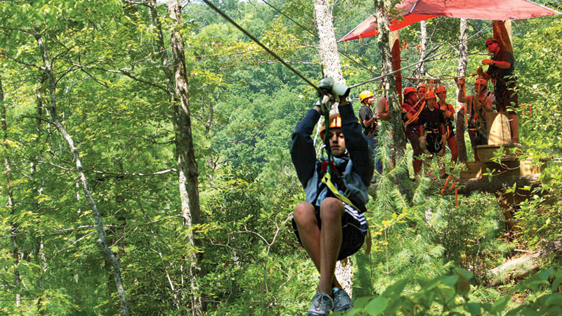 Girl riding a zip line through the trees